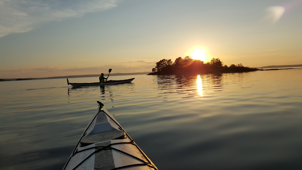One person canoeing on a very calm water in the sunset